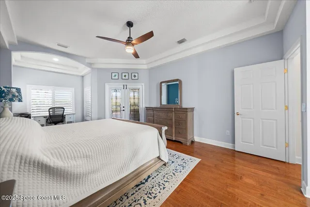 a spacious bedroom with a large bed a chandelier and a dresser