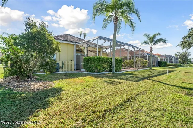 a view of a house with a big yard and palm trees
