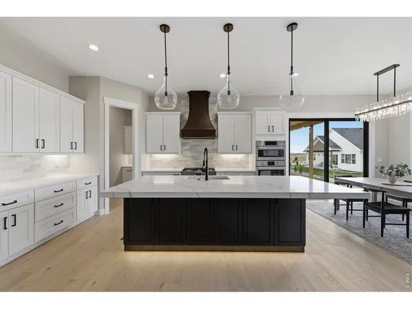 a kitchen with kitchen island sink stove and white cabinets with wooden floor