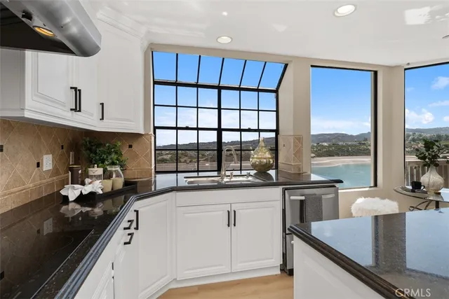 a kitchen with granite countertop a sink and white cabinets