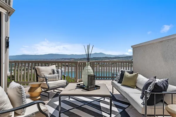 a roof deck with a couches and chairs with wooden floor