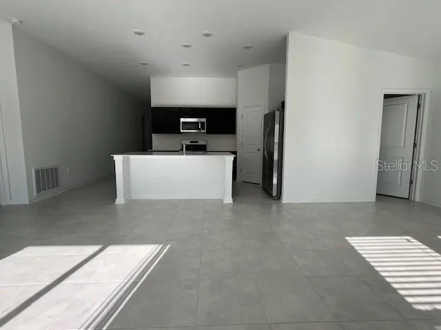 a living room with stainless steel appliances furniture a refrigerator and a fireplace