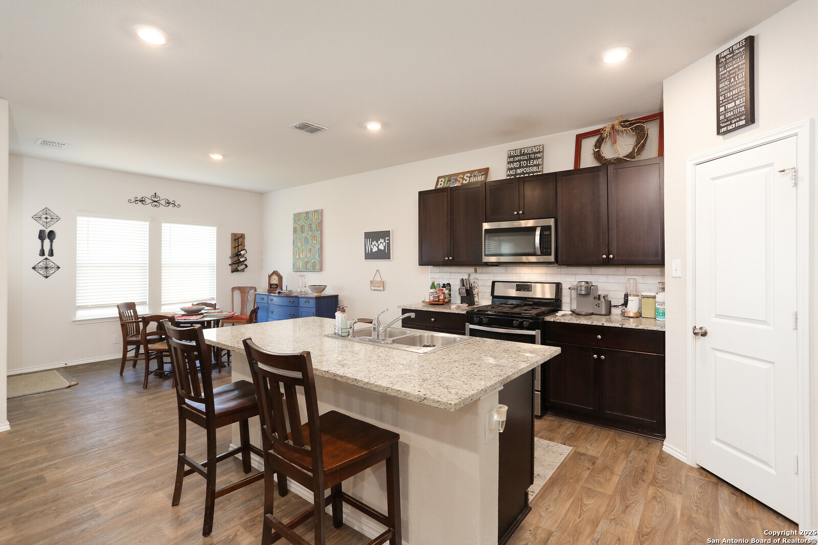 132 Bunkers Hl Road Floresville, TX 78114 - Photo 6 of 27 a kitchen with stainless steel appliances granite countertop a stove a sink a microwave a refrigerator a dining table and chairs