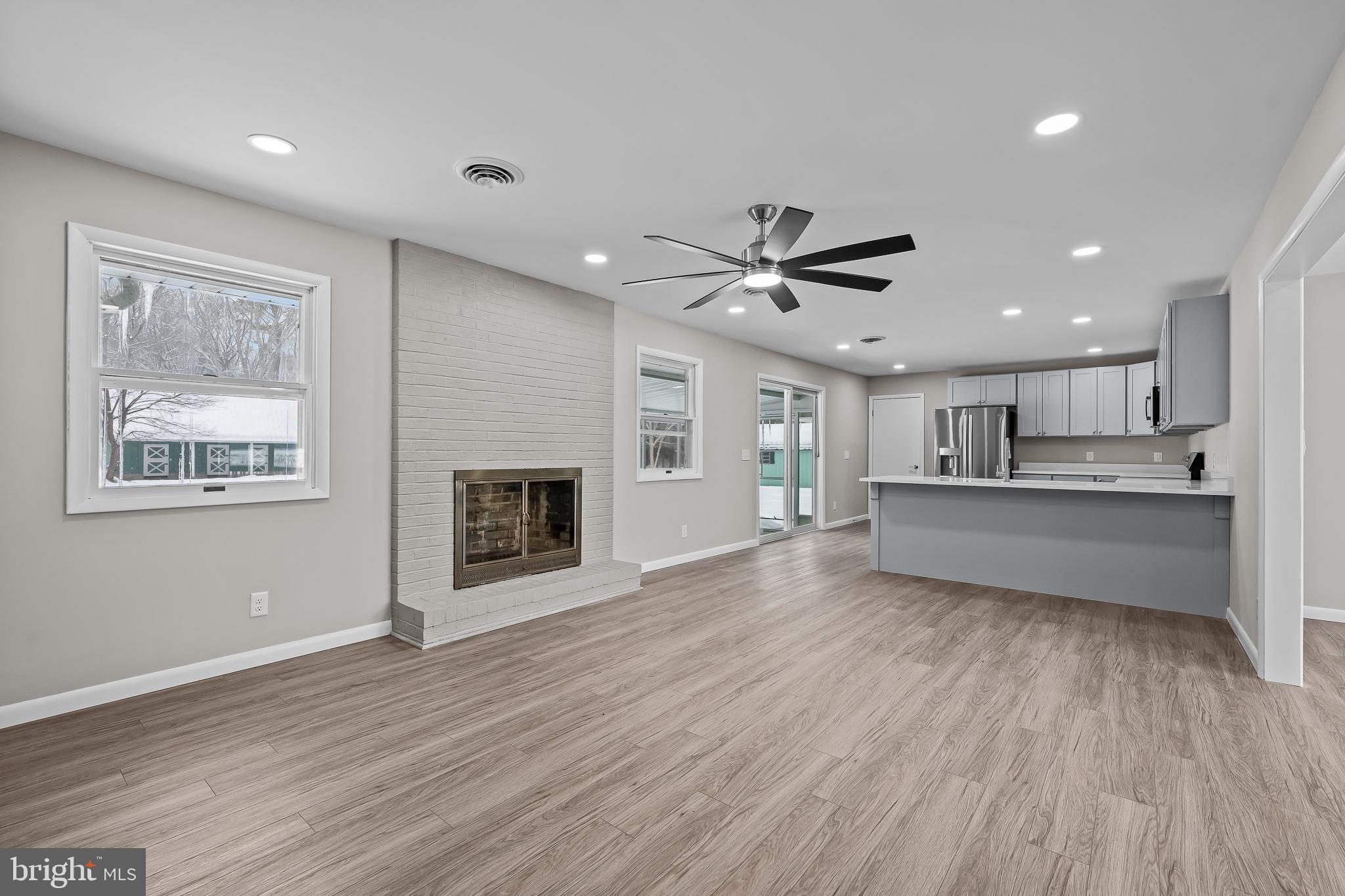 21830 Vaughn Road Georgetown, DE 19947 - Photo 5 of 39 an empty room with wooden floor a kitchen view and a window