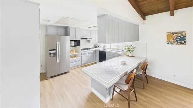 a kitchen with stainless steel appliances a dining table chairs and refrigerator