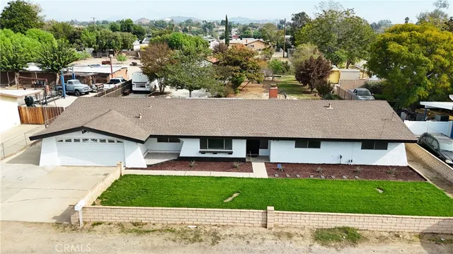 a view of a big house with a big yard plants and large tree