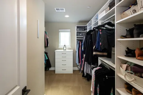 a view of walk in closet with clothes and shoes