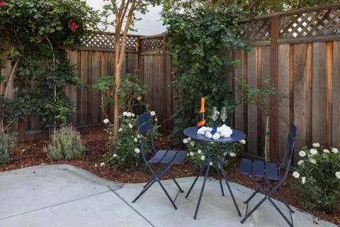 a backyard of a house with table and chairs plants