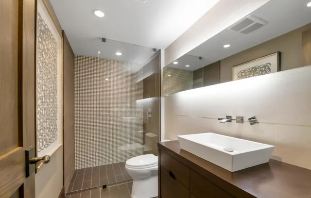 a bathroom with a sink a toilet a mirror and shower