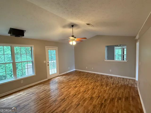 a view of an empty room with window and wooden floor