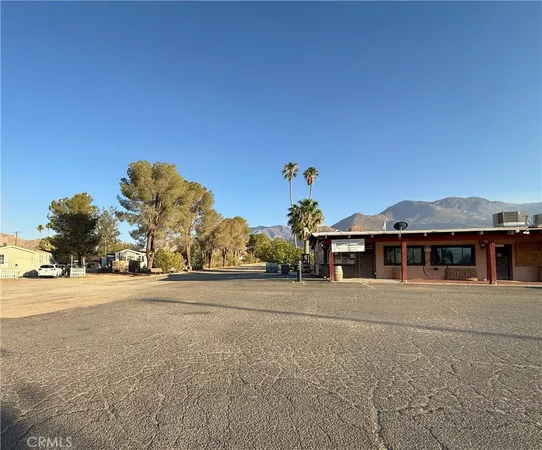a front view of a building with a yard and palm trees