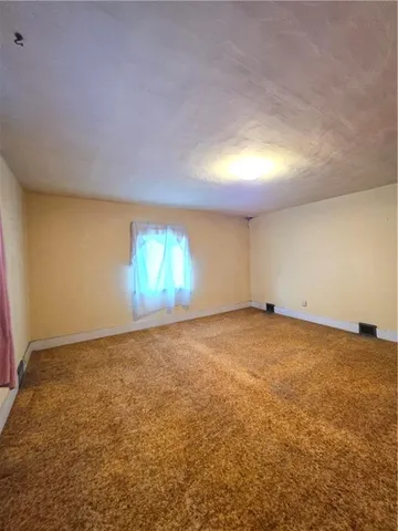 an empty room with windows and fireplace