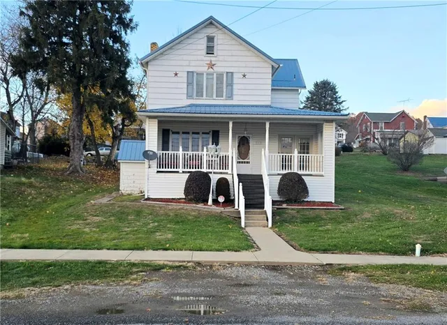 a front view of a house with a garden and trees