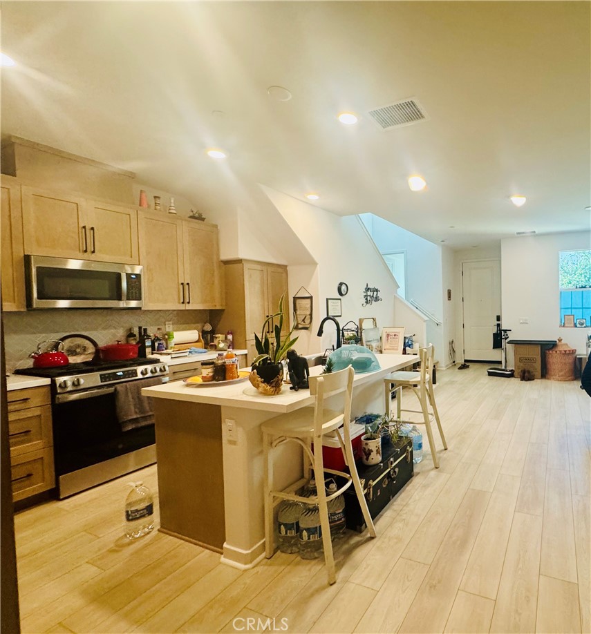 3972 Lavine Way, Unit 110 Corona, CA 92883 - Photo 4 of 9 a kitchen with stainless steel appliances kitchen island granite countertop a stove top oven a sink a dining table and chairs