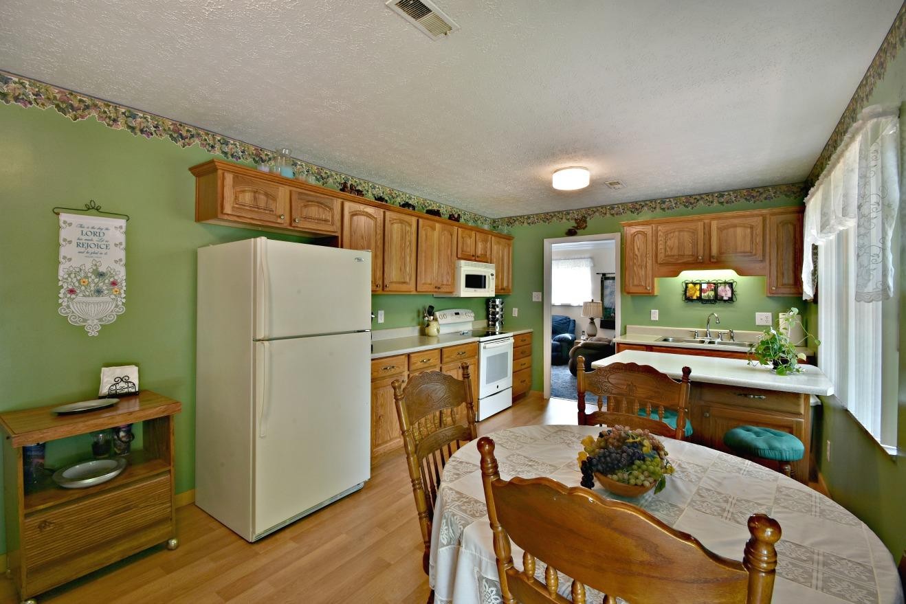 6100 McNeely Road Corryton, TN 37721 - Photo 6 of 17 a kitchen with stainless steel appliances granite countertop a refrigerator a stove a sink a dining table and chairs with wooden floor