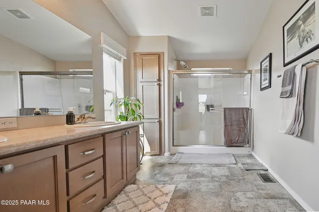 a bathroom with a granite countertop sink a mirror a shower and a vanity