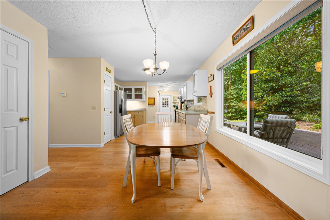 139 Tulip Lane Westminster, SC 29693 - Photo 26 of 37 A well-lit eat-in kitchen with warm wood flooring opens to a serene, tree-lined view, creating a peaceful dining atmosphere.