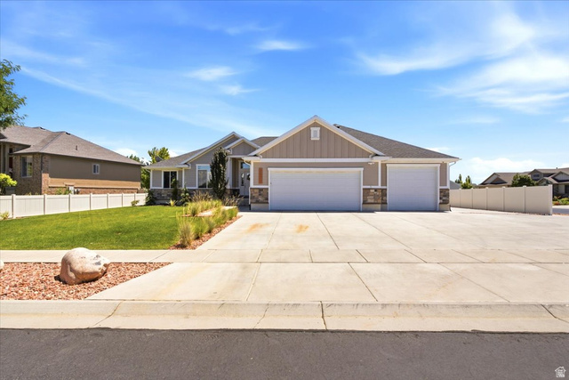 2973 West Red Sand Rd Haven Ogden, UT 84401 - Photo 5 of 30 Ranch-style residence featuring a split three-car garage, stone and siding exterior, concrete driveway, front yard landscaping with grass and decorative rock, and a white privacy fence