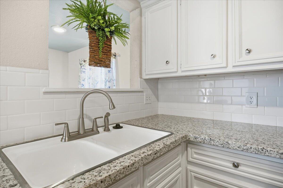 2301 92nd Street Lubbock, TX 79423 - Photo 11 of 30 a kitchen with granite countertop a sink a potted plant and cabinets