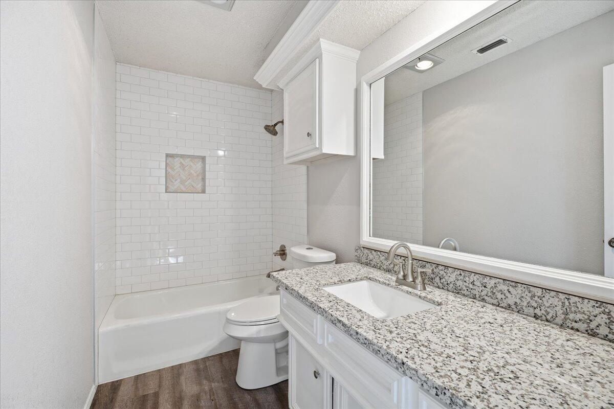 2301 92nd Street Lubbock, TX 79423 - Photo 21 of 30 a bathroom with a granite countertop sink a toilet and shower