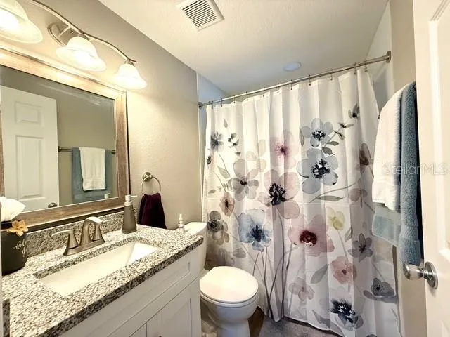 a bathroom with a granite countertop sink toilet and shower