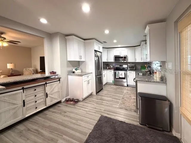 a large kitchen with stainless steel appliances lots of counter space and wooden floors