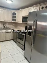 a kitchen with granite countertop a refrigerator and a stove top oven