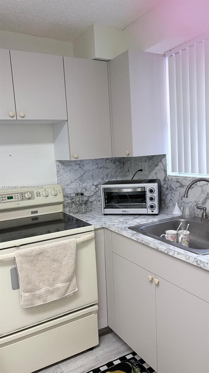 199 Southwest 12th Avenue, Unit 415B Miami, FL 33130 - Photo 17 of 39 a kitchen with granite countertop white cabinets and white appliances