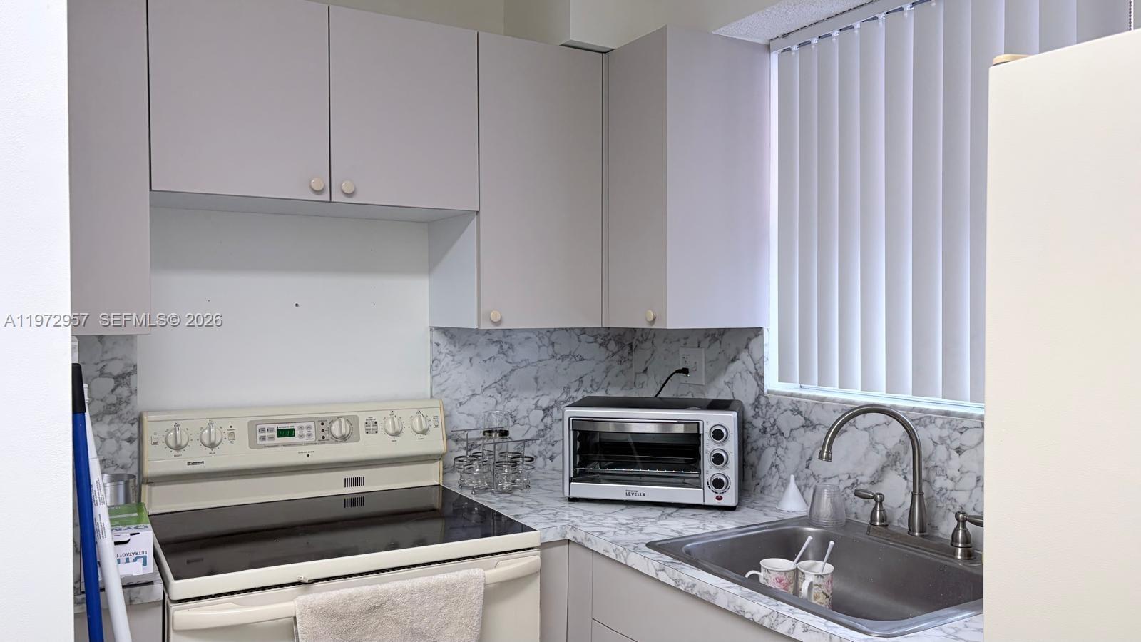 199 Southwest 12th Avenue, Unit 415B Miami, FL 33130 - Photo 18 of 39 a kitchen with granite countertop a stove top oven cabinetry a sink and dishwasher