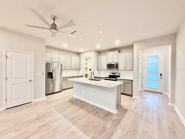 a large white kitchen with a refrigerator a stove top oven a sink and a center island