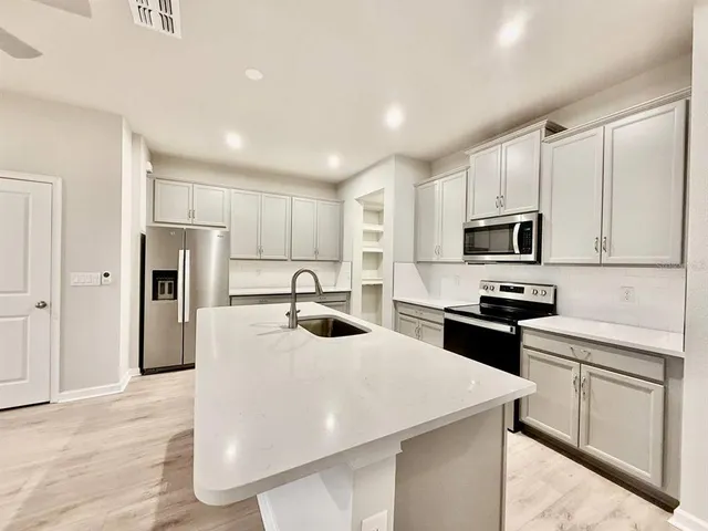 a kitchen with stainless steel appliances a stove refrigerator sink and microwave