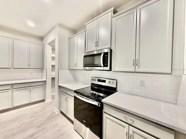 a kitchen with stainless steel appliances a stove microwave and white cabinets