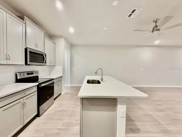a kitchen with sink a microwave and cabinets