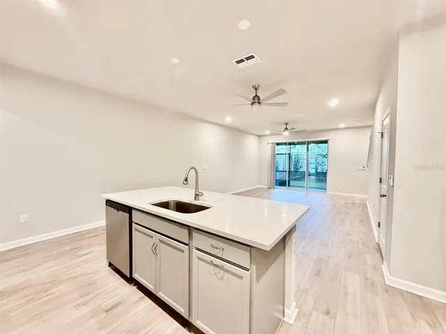 a kitchen with a sink dishwasher and white cabinets with wooden floor