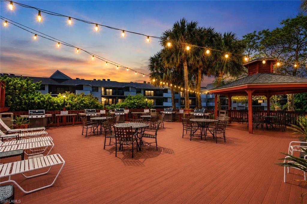 600 Neapolitan Way, Unit 449 Naples, FL 34103 - Photo 32 of 44 Spacious outdoor deck featuring multiple dining areas, a gazebo, and string lighting