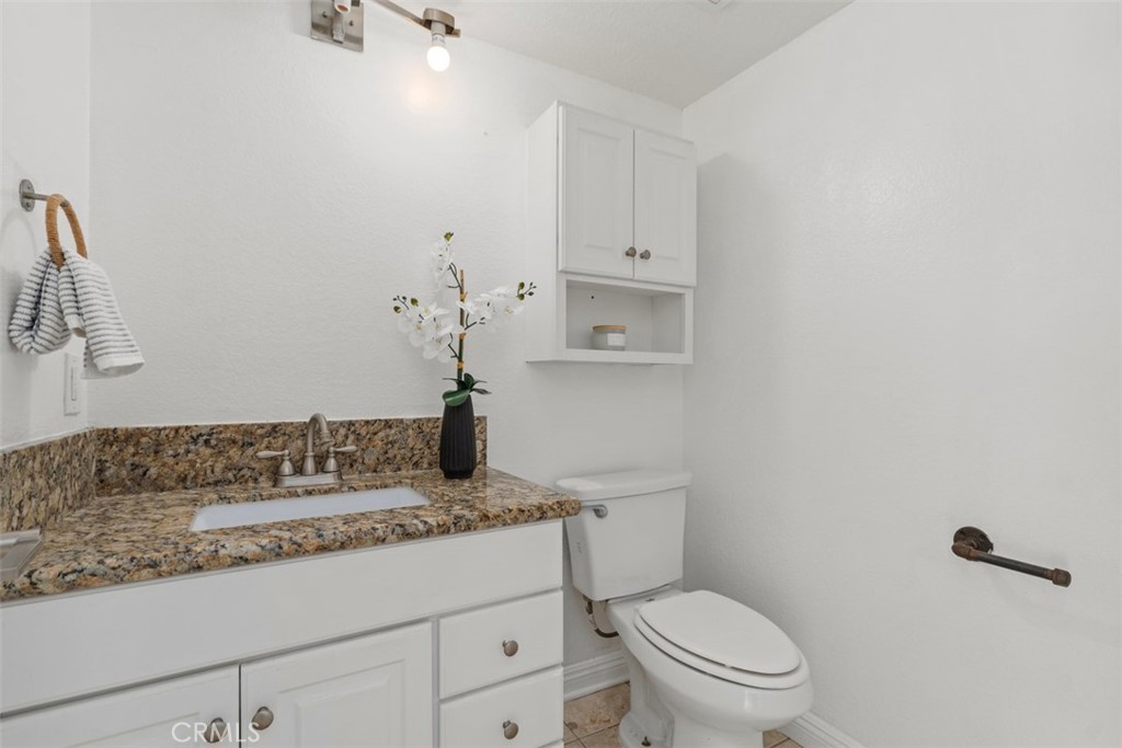 25885 Trabuco Road, Unit 203 Lake Forest, CA 92630 - Photo 21 of 43 a bathroom with a granite countertop sink a toilet and mirror