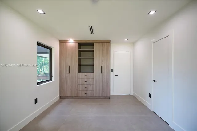 a view of an empty room with window and cabinet