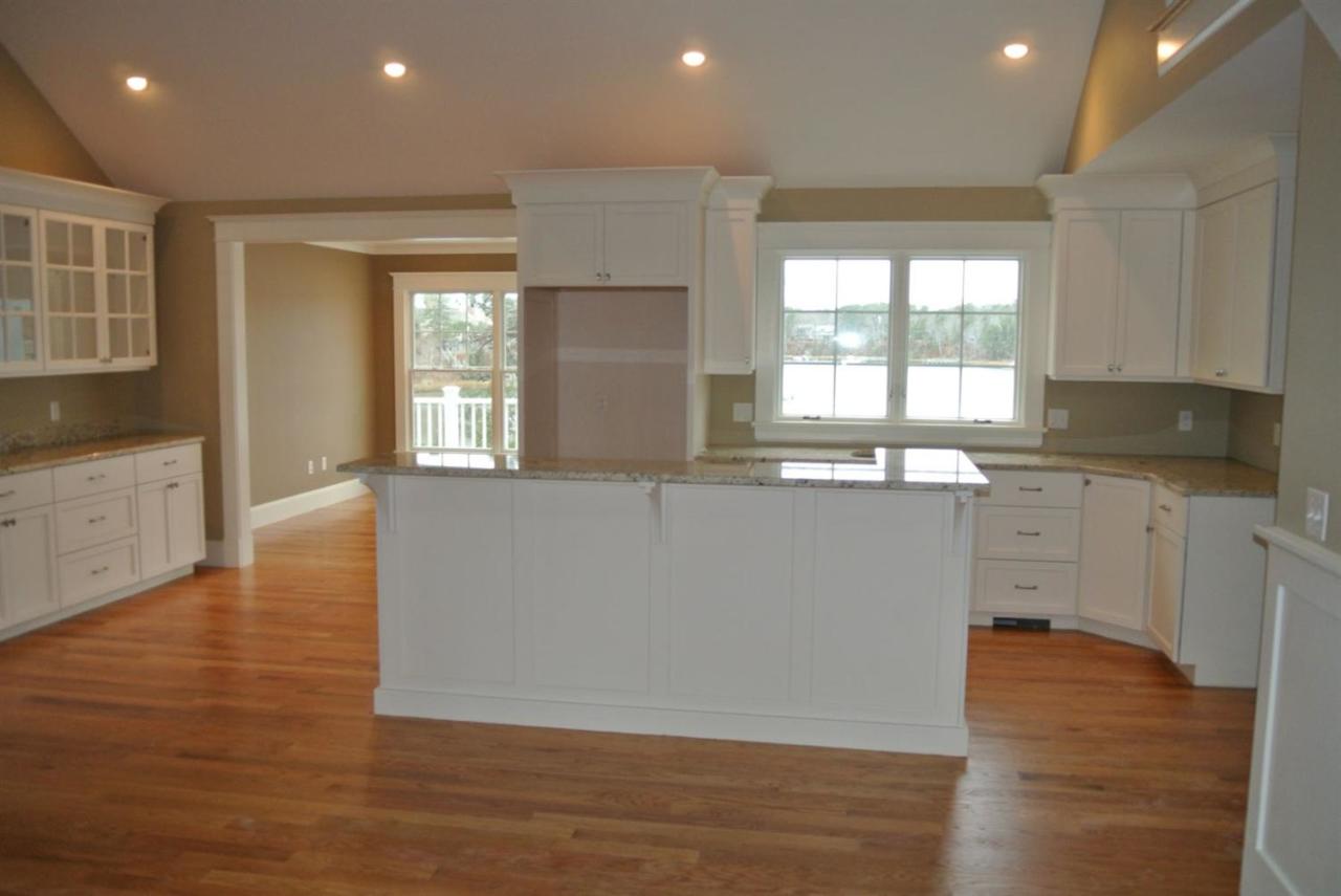 114 Summersea Road, Unit 90 Mashpee, MA 02649 - Photo 4 of 24 a large kitchen with granite countertop a stove a sink a refrigerator and white cabinets with wooden floor