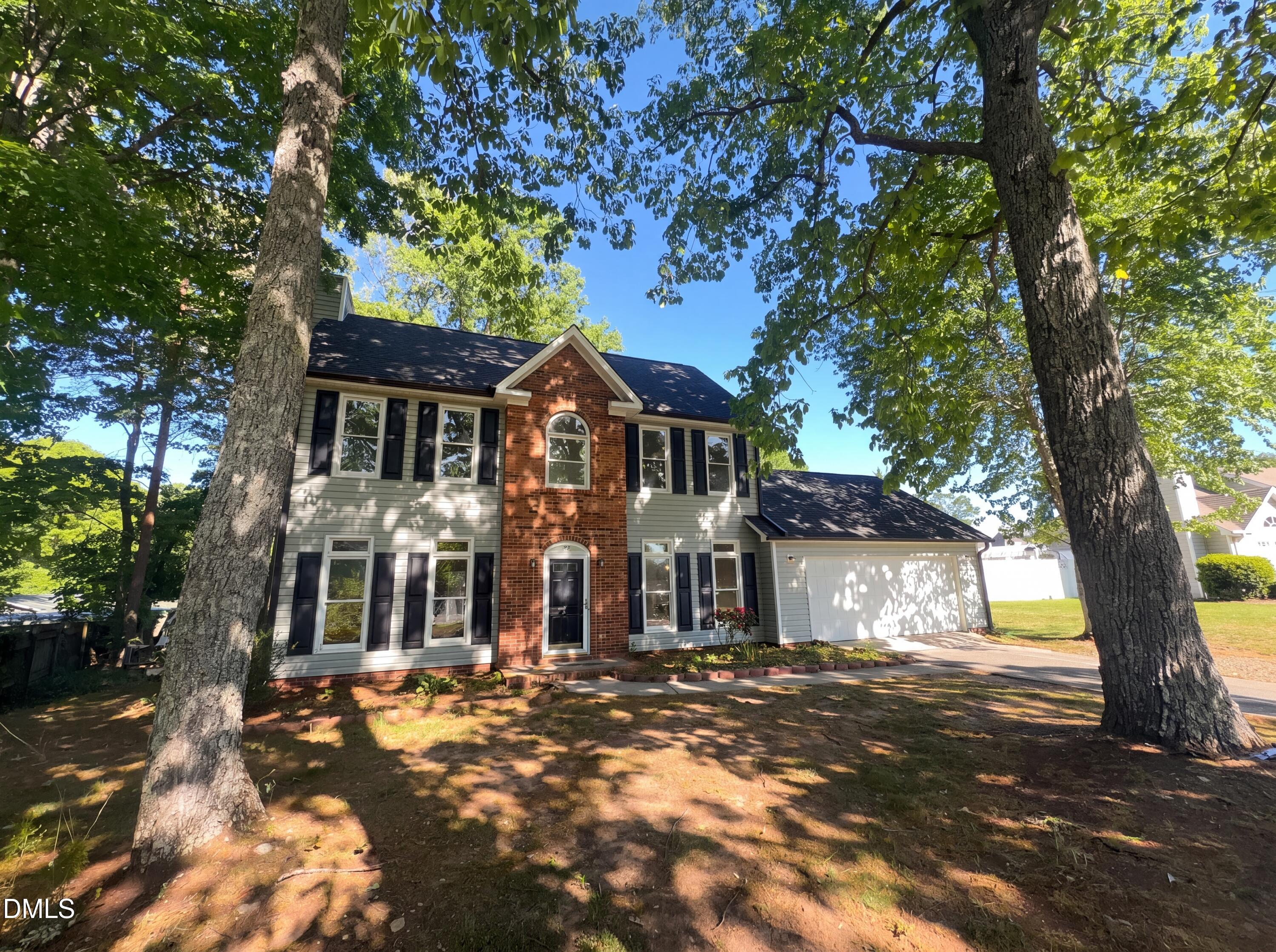 a front view of a house with a yard and tree s