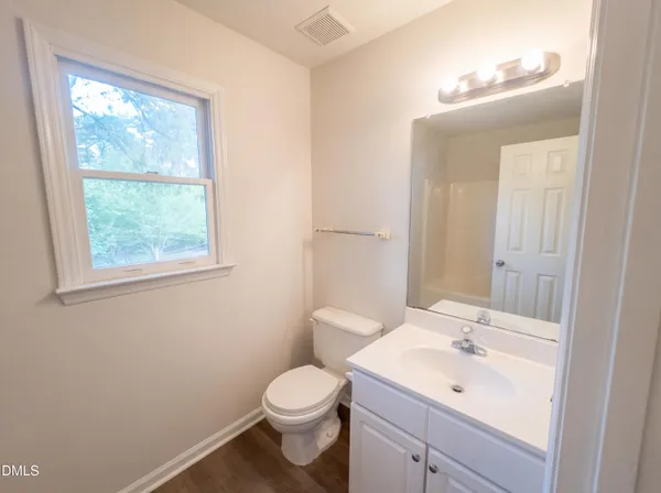 a bathroom with a toilet a sink a mirror and a window
