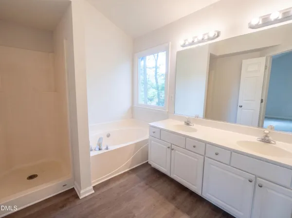 a spacious bathroom with a tub sink and mirror