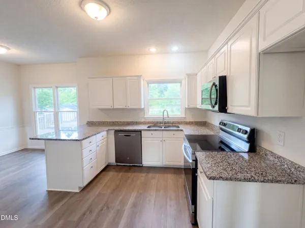 a kitchen with granite countertop white cabinets and white appliances