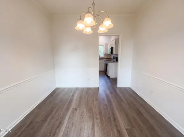a view of a hallway with wooden floor and a kitchen