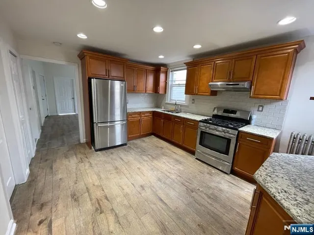 a kitchen with stainless steel appliances granite countertop a refrigerator a stove top oven a sink and dishwasher