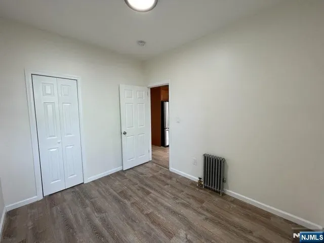 a view of an empty room with wooden floor and closet