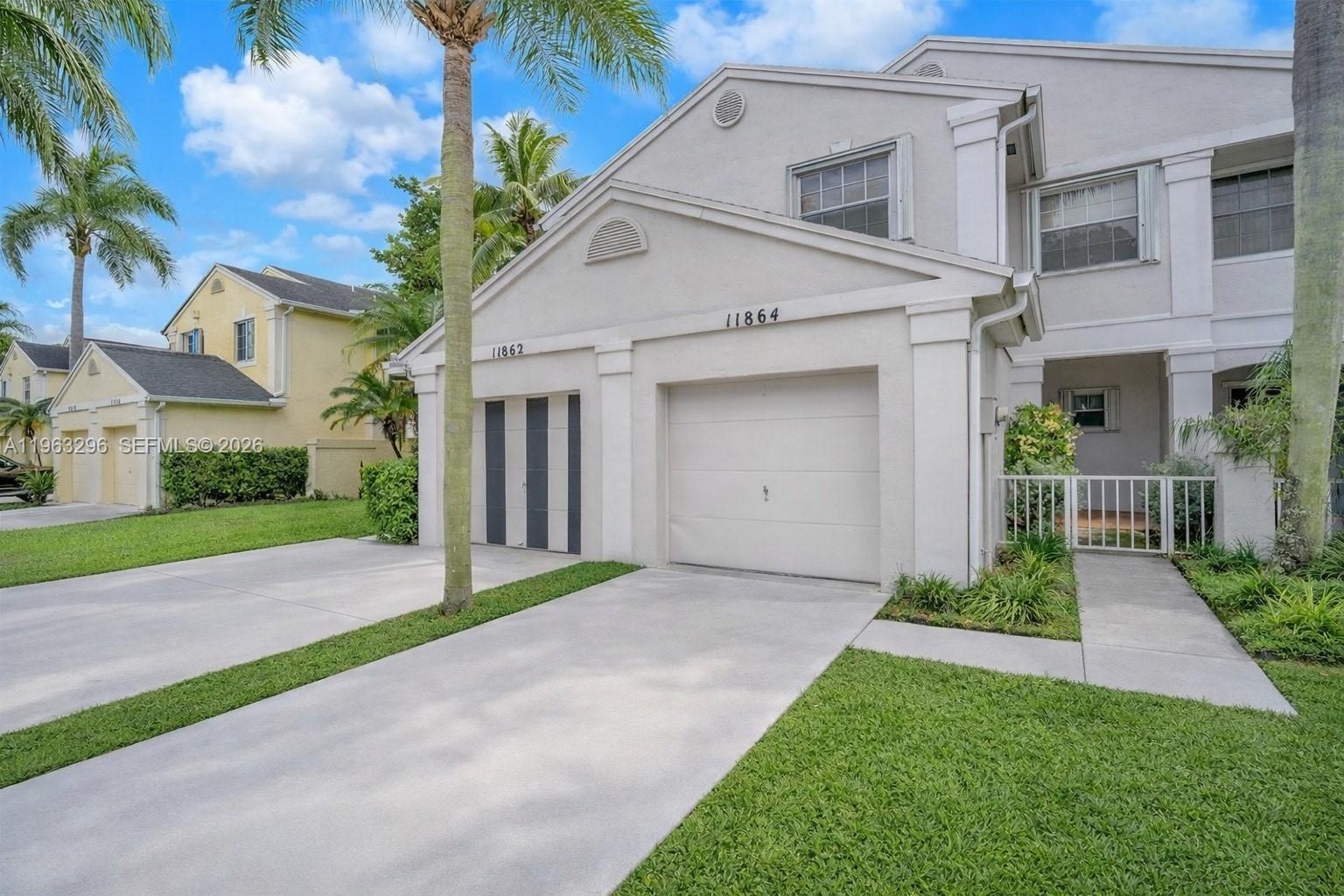 a view of a white house next to a yard and palm trees