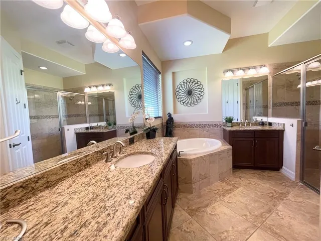 a large bathroom with a granite countertop sink a large mirror and bathtub