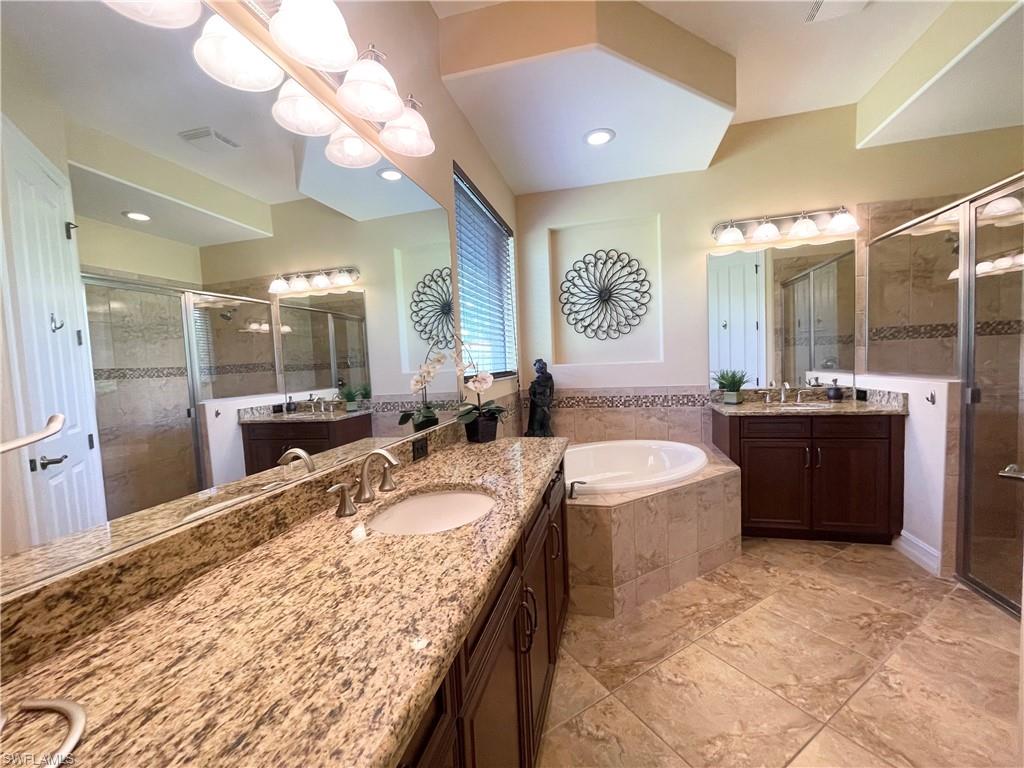 7302 Acorn Way Naples, FL 34119 - Photo 20 of 40 a large bathroom with a granite countertop sink a large mirror and bathtub
