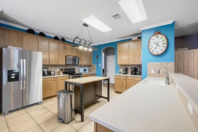 a large kitchen with cabinets a refrigerator and a stove top oven