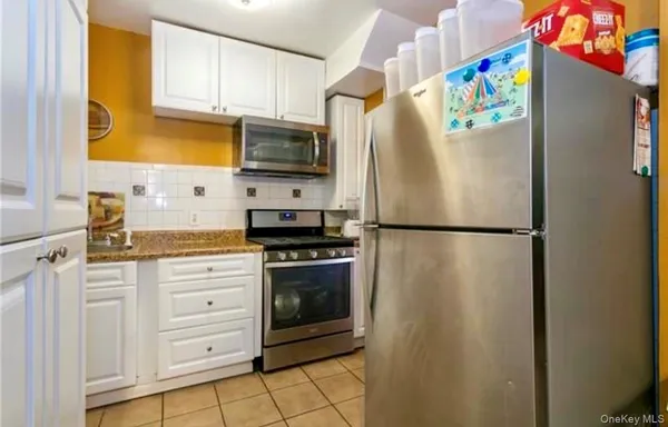 a kitchen with stainless steel appliances granite countertop a refrigerator a stove a sink and a microwave